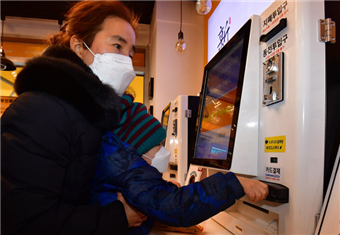 중증 시각장애인 김경미씨와 아들이 지난달 18일 서울 자택 근처 무인 슈퍼마켓에서 물건을 산 뒤 키오스크에서 결제하고 있다. 김씨가 아들을 들어 올려 신용카드를 기계에 넣을 수 있게 했다. 
