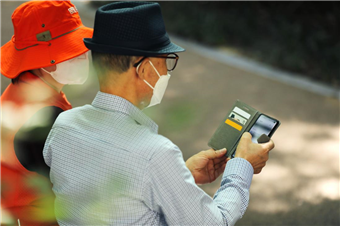서울시 디지털 안내사가 한 어르신에게 스마트폰 와이파이 설정하는 법을 설명하고 있는 사진