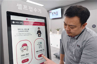 LG전자 서비스엔지니어가 서울 광진구에 위치한 LG전자 광진서비스센터에 설치된 키오스크에서 디지털휴먼의 수어 안내를 받아 서비스를 접수하는 방법을 안내하고 있다. [사진=LG전자]